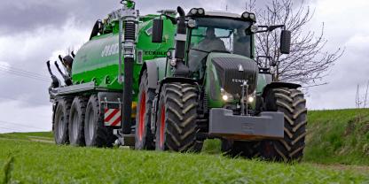 Traktor der Marke Fendt mit einem Güllefass auf der Strasse.