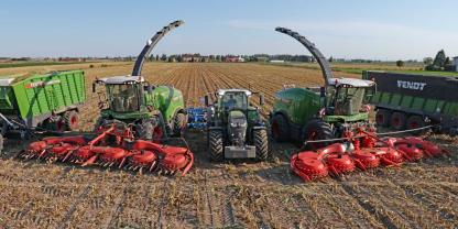 Landmaschinen von Fendt auf einem geernteten Maisfeld.