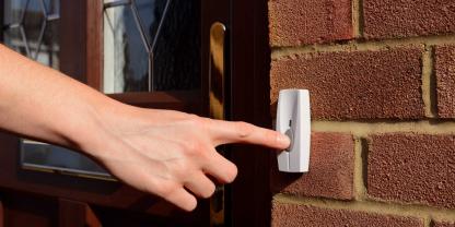 Eine Hand klingelt an einer Haustür Eine Hand klingelt an einer Haustür